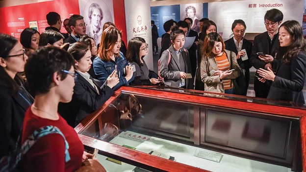 People looking at an item in exhibition case