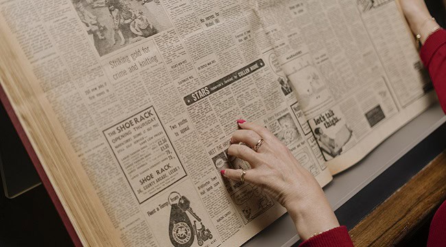 Newspaper positioned upright with hands.